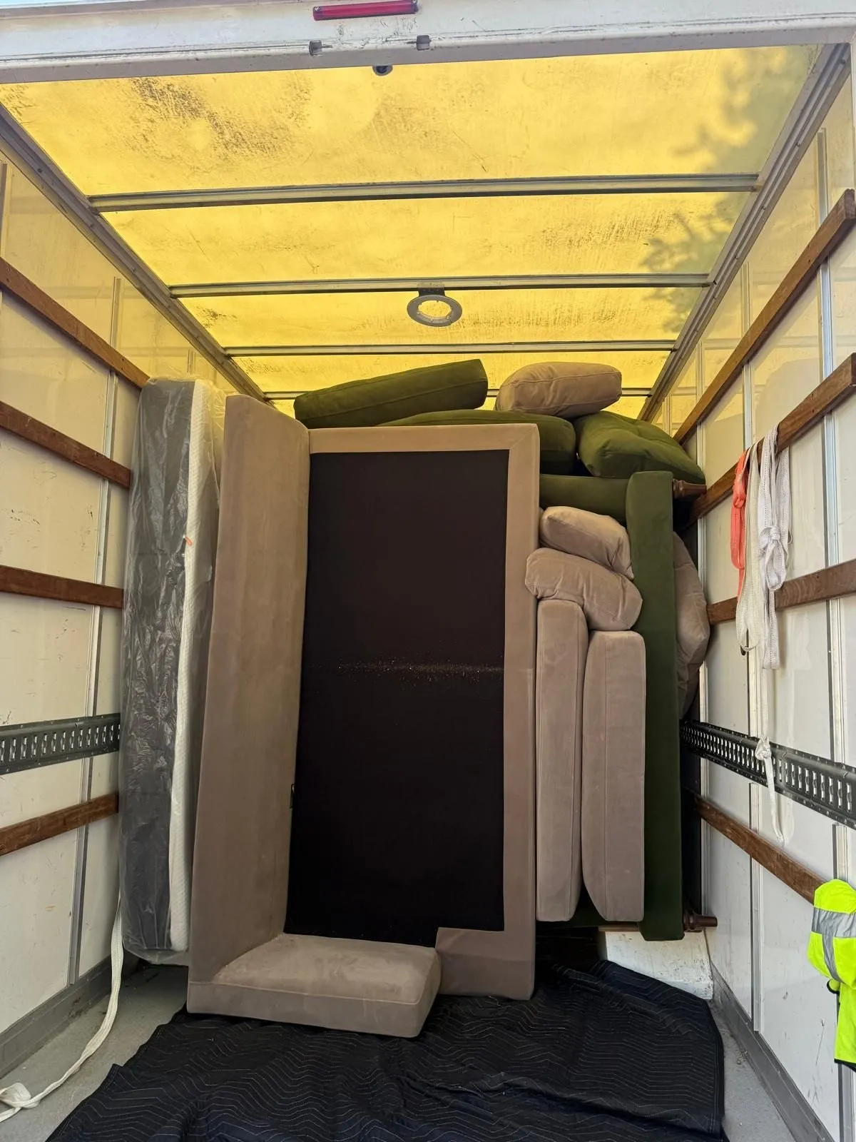 Removal team carrying wrapped furniture from a house to a van